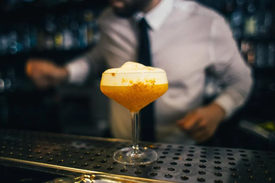 Une coupe posée sur le comptoir, le barman en fond