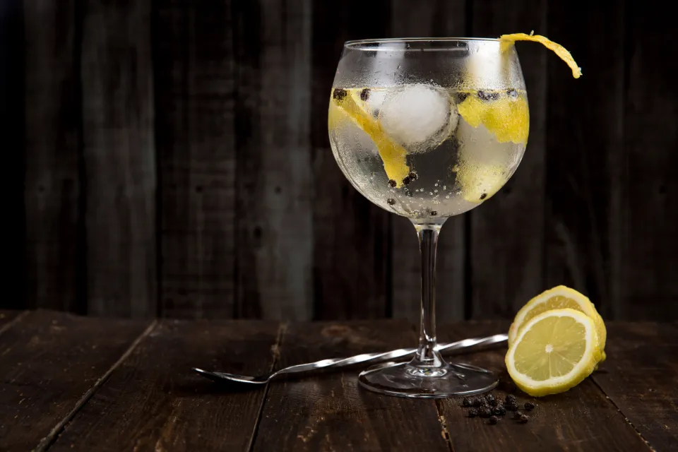 Un cocktail au gin, zeste de citron, sur fond sombre