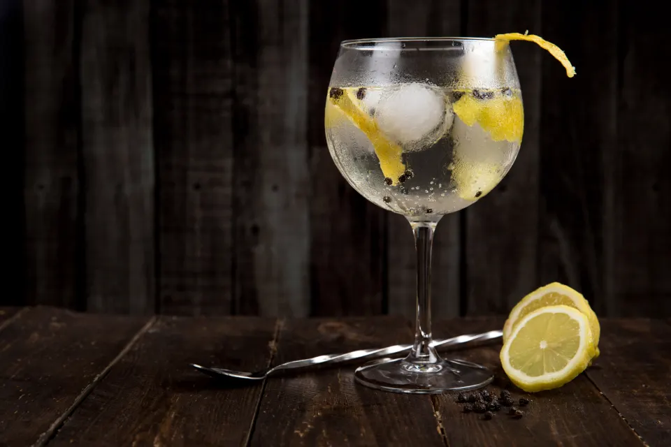 Un cocktail au gin, zeste de citron, sur fond sombre